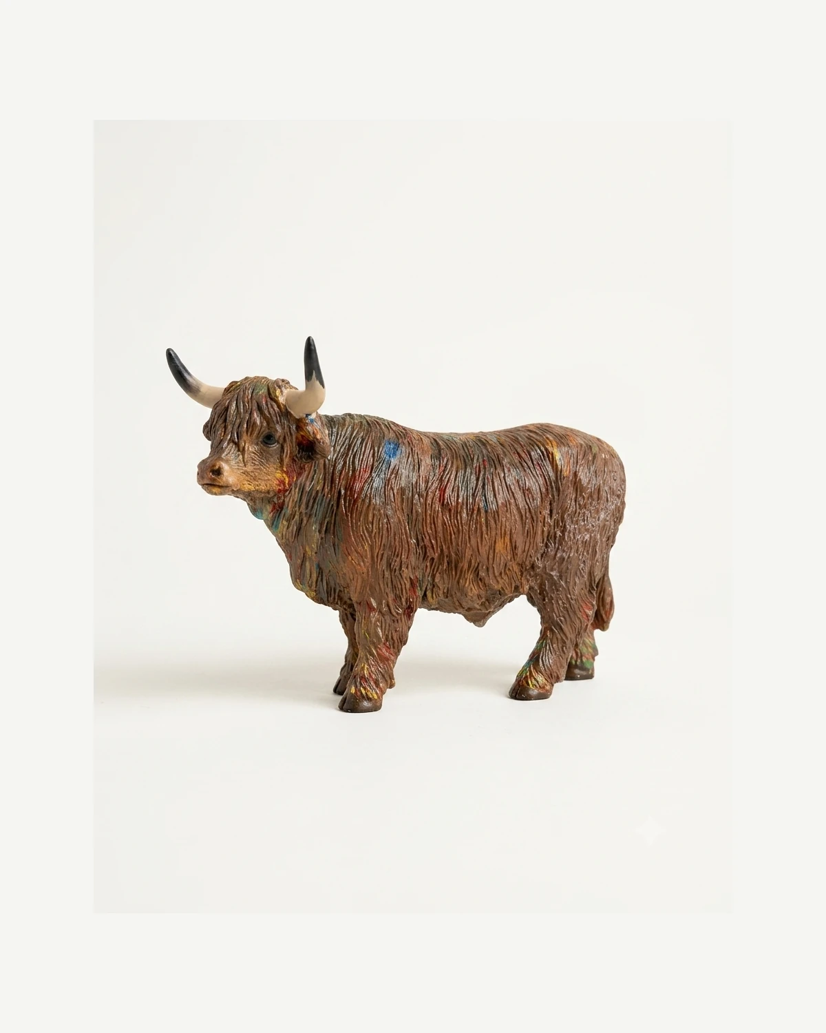 Toro decorativo de pelo largo en tonos marrón con detalles multicolor, vista principal.